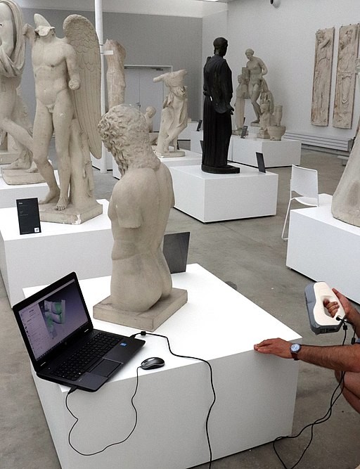 Zu erkennen ist ein PC, der neben einer Statue platziert ist, während eine Person diese mit einen Handscanner digitalisiert.