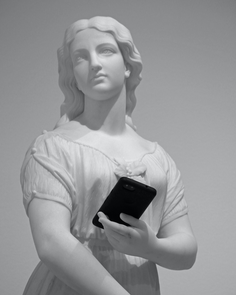 Großaufnahme einer Statue, die ein Smartphone in der Hand hält.