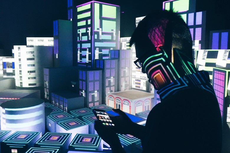 Ein Mann hält ein Smartphone in der Hand in einem graphisch-farbigen Raum.