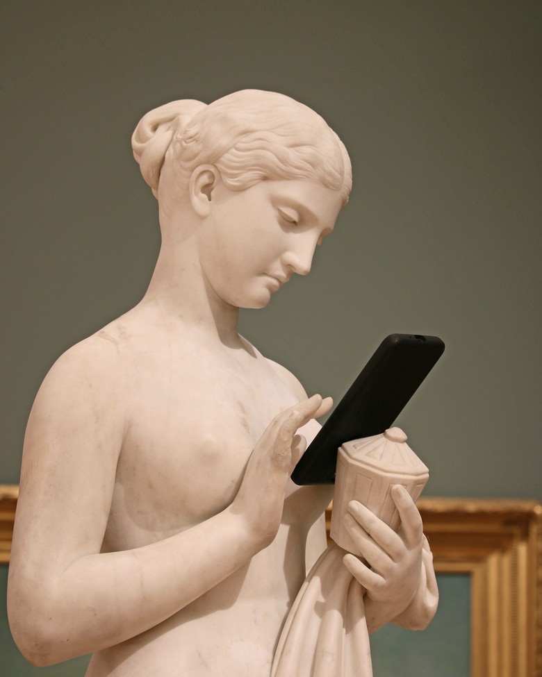 Eine Statue hält ein Smartphone in der Hand.