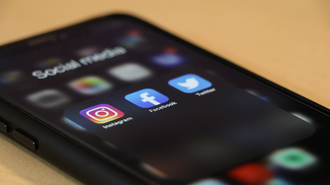 Drei Social Media Apps leuchten auf einem Smartphone Screen auf.
