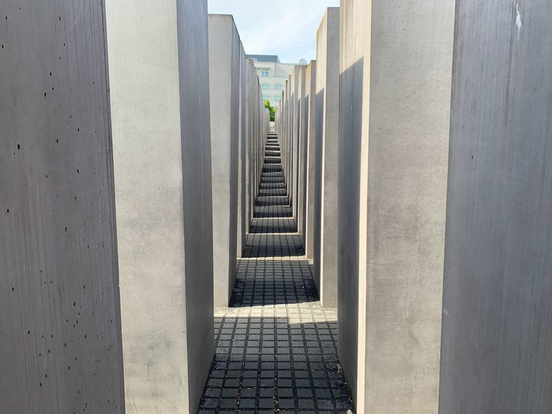 Zu sehen ist ein Gang der durch die Steine des Holocaust Denkmals in Berlin führt.